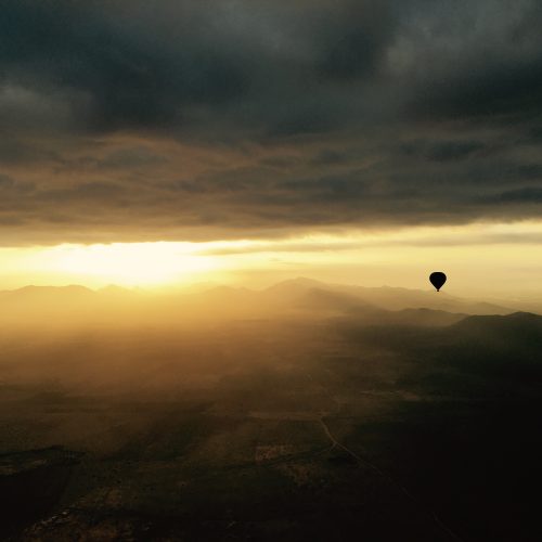 A Marrakech Hot Air Balloon flying under clouds with Atlas mountains view